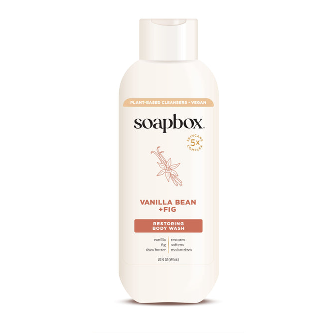 Soapbox Nourishing Body Wash, in a white bottle with floral illustrations and brown accents, features a vanilla bean, fig scent with yuzu lemon hints. The label emphasizes its natural vegan ingredients that restore and moisturize the skin.