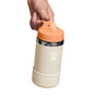 A hand holds a 12 oz Kids Stainless Steel Wide Mouth Hydro Flask bottle featuring a cream color with a peach cap and boot. The bottle has the signature logo, double-wall vacuum insulation to keep drinks cold, and a loop handle on the BPA-free straw cap for easy carrying.