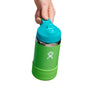A hand holds a green and blue Hydro Flask Kids Stainless Steel Wide Mouth Bottle with Straw Cap & Boot, 12 oz. This BPA-free bottle has double-wall vacuum insulation, an ergonomic design, stylized water droplet logo, and a firm grip.
