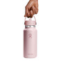 A hand grips a pink Hydro Flask Wide Mouth Bottle with Flex Straw Cap, 32 oz, showcasing its sleek design and silver band. Double-wall insulation keeps drinks at the perfect temperature, while the minimalist background highlights its modern allure.