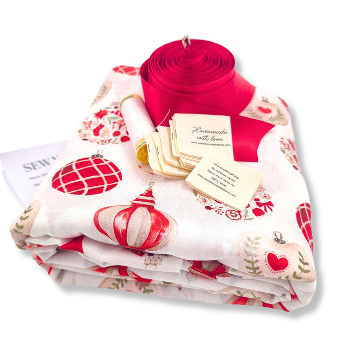 The Sew Your Own Set of 10 gift bags - Candy Cane Baubles by Waste Free Celebrations includes festive red and white fabric, ribbon, sewing pattern, and “Homemade with love” tags—everything needed for DIY reusable Christmas gift bags.