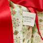A close-up of a Waste Free Celebrations Set of 10 Reusable Gift Bags in a Folk Art Geometric pattern, partially covered by a red ribbon. A tag highlights them as a sustainable, waste-free alternative made in Afghanistan.