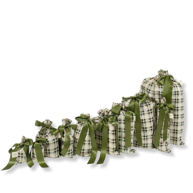 A set of 10 reusable tartan gift bags by Waste Free Celebrations, each featuring a large green satin ribbon, arranged in ascending size for a stylish, sustainable gift wrap—crafted from 100% cotton.