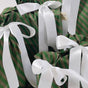 Several gifts in Waste Free Celebrations Set of 5 Reusable Gift Bags - Green Stripes are tied with large white satin ribbons, creating a festive and elegant appearance.