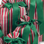 The Set of 5 Reusable Gift Bags - Traditional Stripes by Waste Free Celebrations features red, white, and green striped bags with large green satin bows, stacked together for a festive look and eco-friendly alternative to wrapping paper.