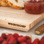 The Alto Raised Wood Board by WoodForChef, crafted from 100% FSC certified maple, rests beside a knife, raspberries, sliced bread, and a glass bowl of red jam.