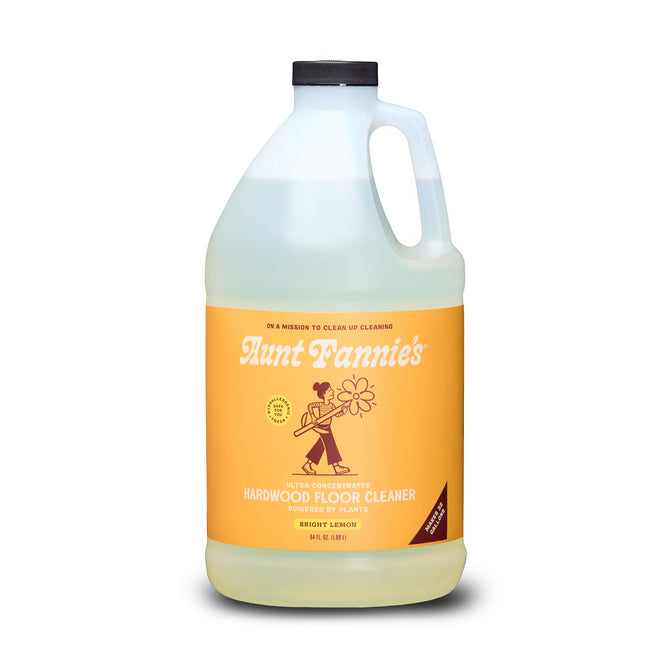 Aunt Fannie's Hardwood Floor Cleaner, Value Size, comes in a clear gallon jug with black cap and orange label featuring vintage-style design. This lemon-scented natural cleaner is made with essential oils.