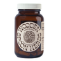 A brown glass bottle labeled Brain Bloom Capsules by Wooden Spoon Herbs holds 60 capsules. It features a round beige label with wavy text, a brain illustration, and contains nootropic herbs to support cognitive function.