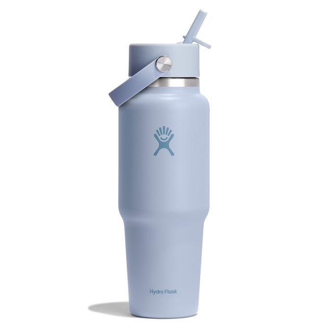 A 32 oz light blue Hydro Flask Wide Mouth Travel Bottle with Flex Straw Cap features the brand logo and a lid with a carrying handle, casting a subtle shadow on a white background.