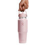 A hand grips a Hydro Flask Wide Mouth Travel Bottle with Flex Straw Cap, 32 oz, in pink, featuring the iconic logo. Its sleek design stands out against the plain white background.