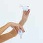 Two hands hold round, white Face Cupping Kit tools by WTHN, made of glass and silicone, against a plain white background. Inspired by Traditional Chinese Medicine, these tools provide an all-natural facelift experience.