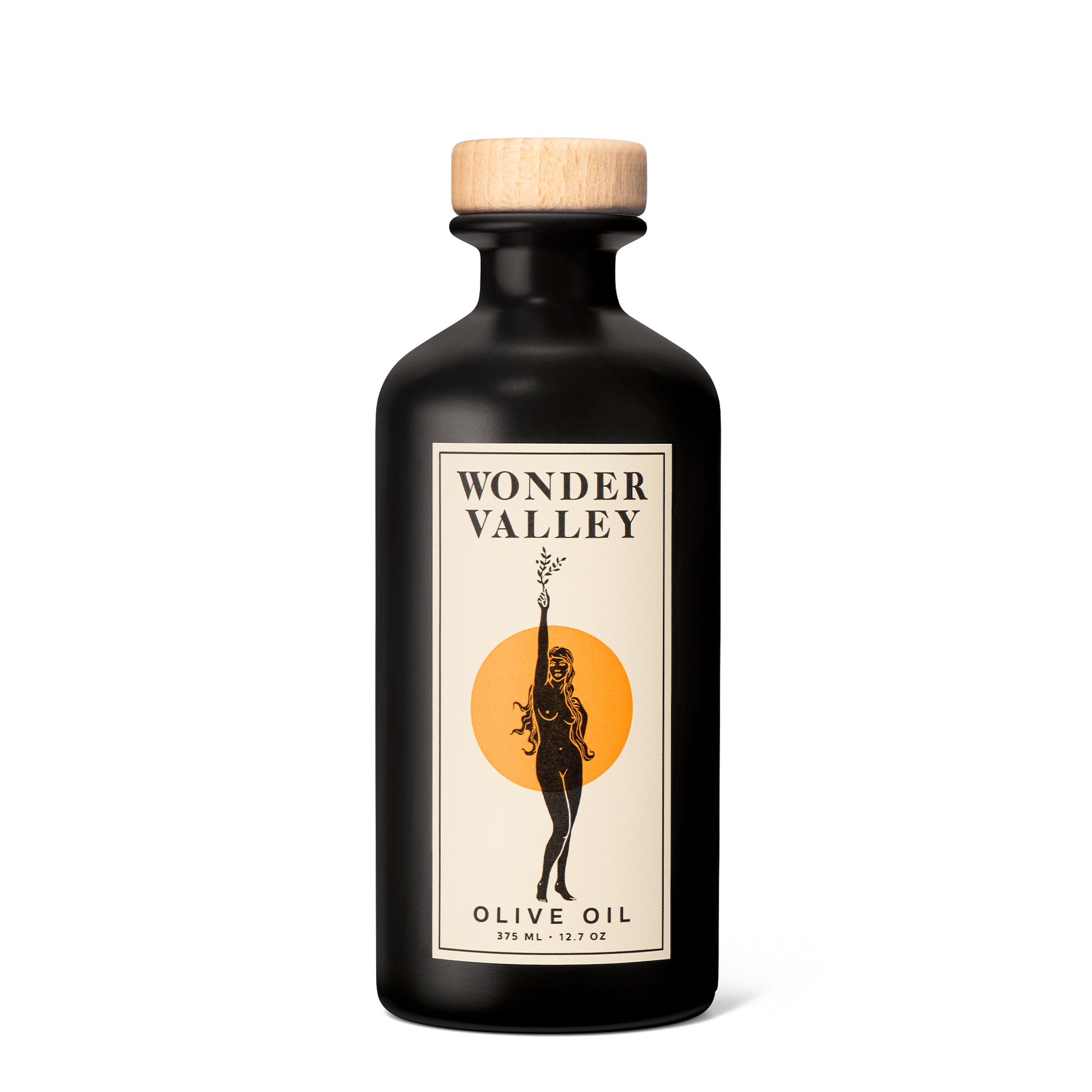 A dark matte bottle of Wonder Valley Olive Oil with a wooden cap features a label depicting a woman holding an olive branch before an orange circle and the text 