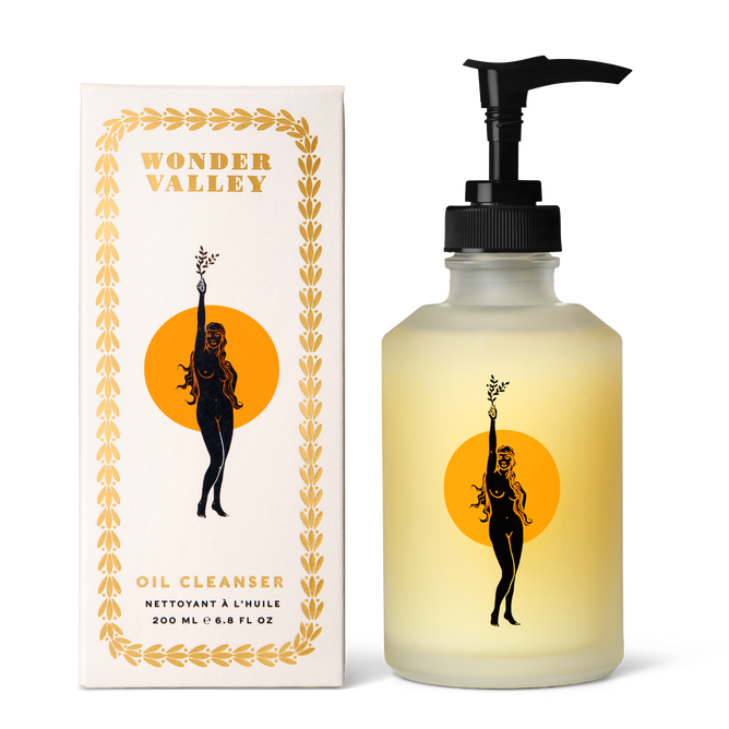 A bottle of Wonder Valley Facial Oil Cleanser with a pump stands beside its box, both showing a woman with flowing hair holding a branch in front of an orange circle and gold leaf border—a gentle cleanser for hydrated skin.