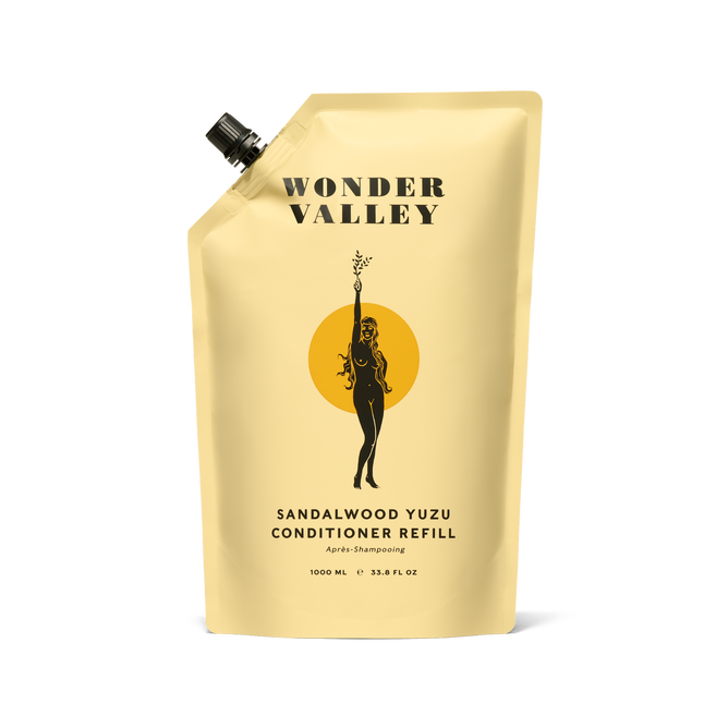 The beige Refill Sandalwood Yuzu Conditioner pouch by Wonder Valley features minimalist text, a black spout on the top left, and a black illustration of a woman holding a branch. The pouch contains a nourishing conditioner formula.