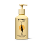A yellow pump-top bottle of Wonder Valley Sandalwood Yuzu Conditioner with black text and a woman-branch illustration on an orange circle, formulated to reduce breakage and boost healthy shine.