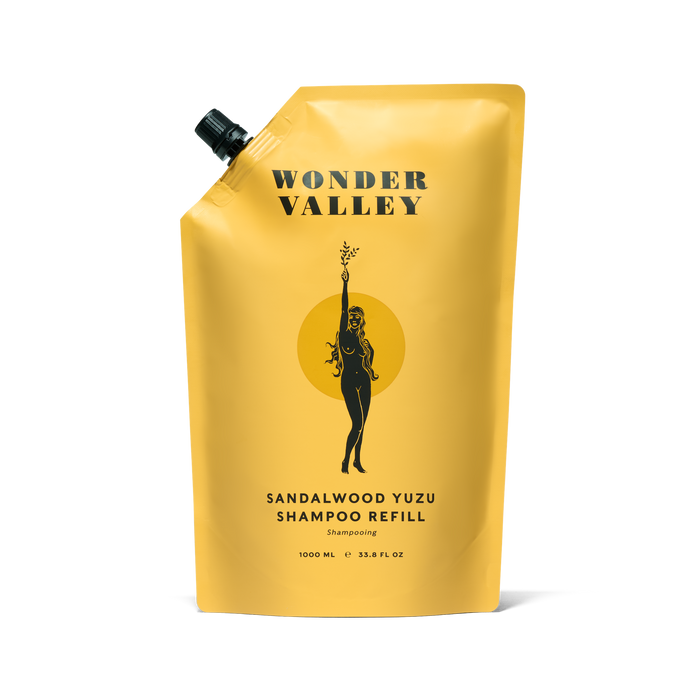 A yellow, 1000 mL pouch of Wonder Valley Refill Sandalwood Yuzu Shampoo features a black-capped design with a figure illustration, ideal for refilling your aluminum bottles and restoring shine to your hair.