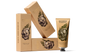 A tube and three boxes of Wonder Valley Seaweed Body Scrub, made with exfoliating sea salt and mineral clays, are arranged artistically. The beige packaging features a lemon, green leaves, and bold product name.