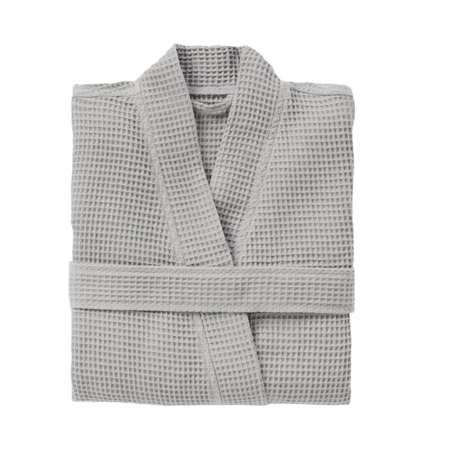 A neatly folded Coyuchi Unisex Organic Waffle Robe in light gray rests on a plain white background, showcasing its textured organic cotton fabric.