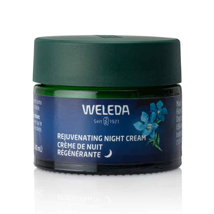 A green jar of Weleda Rejuvenating Night Cream with a dark green lid shows blue gentian and edelweiss on the label. Blue flowers and bilingual text in English and French are visible, all set against a white background.