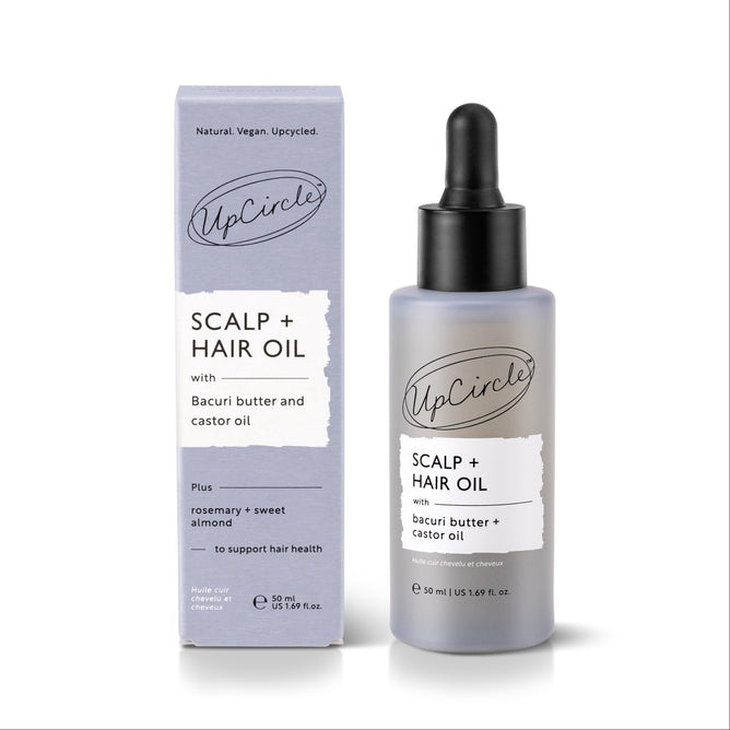 An UpCircle Scalp + Hair Oil with Bacuri Butter and Castor Oil bottle and box. The packaging highlights natural ingredients including rosemary, sweet almond, bacuri butter, and castor oil, and states it is designed to support healthy hair growth.