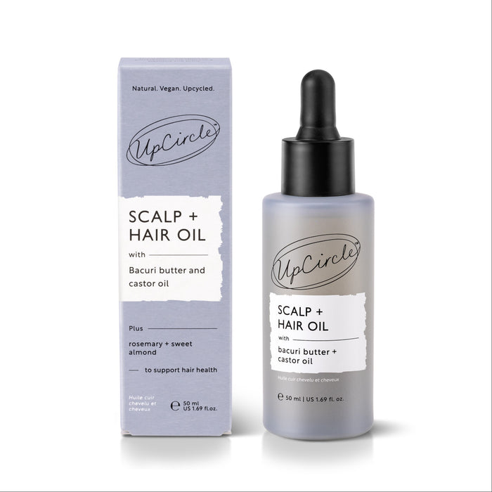 An UpCircle Scalp + Hair Oil with Bacuri Butter and Castor Oil bottle and box. The packaging highlights natural ingredients including rosemary, sweet almond, bacuri butter, and castor oil, and states it is designed to support healthy hair growth.