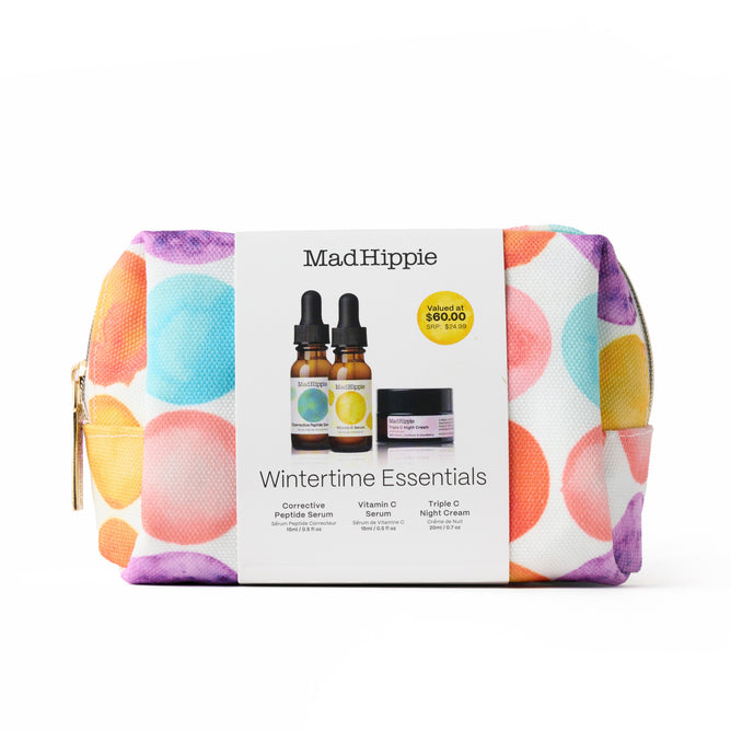 A colorful zippered pouch with large pastel polka dots holds Mad Hippie’s Wintertime Essentials set, featuring Corrective Peptides Serum, Vitamin C Serum, and nourishing Triple C Night Cream.