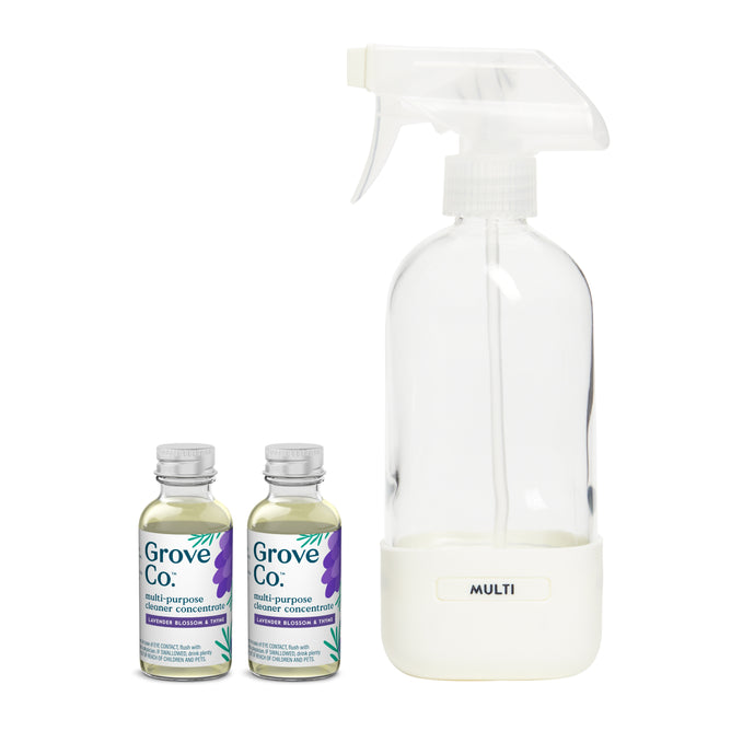 A transparent spray bottle with MULTI stands alongside two Grove Co. Multi-Purpose Cleaner Starter Set concentrate bottles, adorned with purple and blue accents. Made with sustainable packaging, these plant-based cleaners offer a refreshing lavender and thyme scent for eco-friendly cleaning.