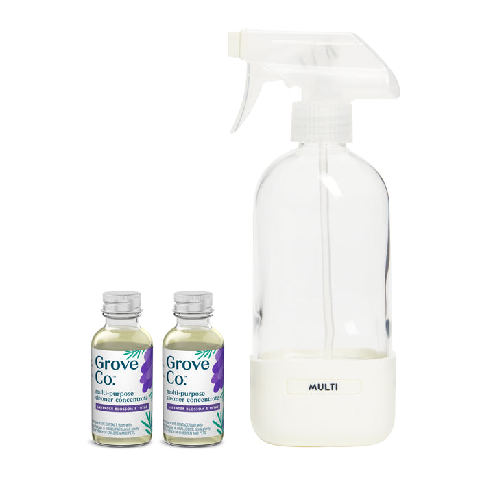 A transparent spray bottle with MULTI stands alongside two Grove Co. Multi-Purpose Cleaner Starter Set concentrate bottles, adorned with purple and blue accents. Made with sustainable packaging, these plant-based cleaners offer a refreshing lavender and thyme scent for eco-friendly cleaning.