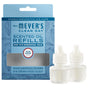 A blue box of Mrs. Meyer’s Scented Oil Refills 2pk sits next to two white diffuser bottles with droppers. The box features product info, floral design, and promotes garden-inspired scents.