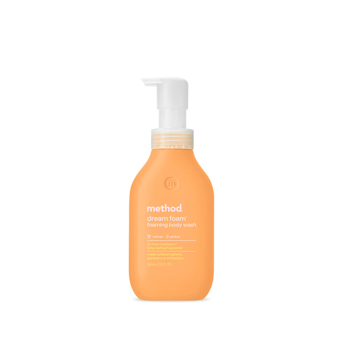 An orange bottle of Method dream foam foaming body wash with a white pump dispenser, labeled “vanilla + amber” fragrance, standing upright on a white background.