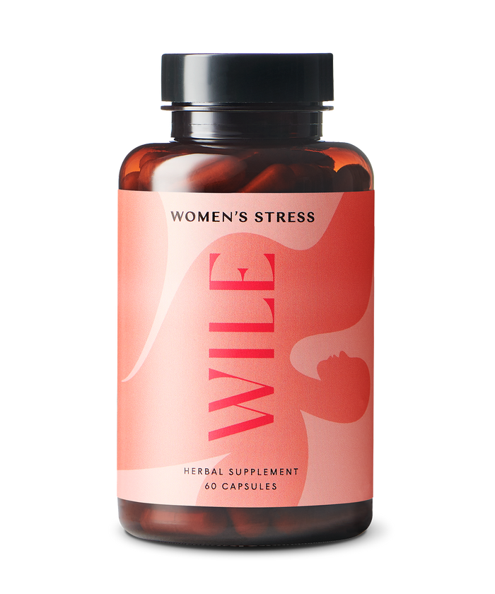 A brown bottle with a black cap labeled WILE Womens Stress, containing 60 herbal supplement capsules. The label features abstract pink and red graphics and text on a light background.