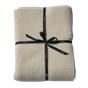 Cream-colored, plant-dyed Adult Popcorn Blanket - Cream folded and tied with a black ribbon.