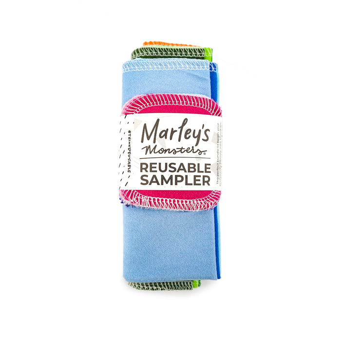 A rolled-up set of colorful reusable cloths with a label reading Marleys Monsters REUSABLE SAMPLER against a white background.