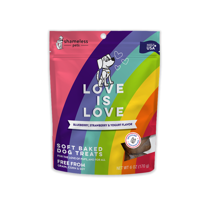A colorful bag of Shameless Pets Love is Love soft baked dog treats, blueberry, strawberry & yogurt flavor. The packaging features rainbow stripes and a cartoon dog, and states it is free from grain, corn, and soy. Net weight 6 oz.
