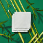 Tree-Free Napkins by Grove Co., made from 100% FSC-certified bamboo, are displayed on a green background with bamboo stalks and leaves arranged in a circle, emphasizing their natural and eco-friendly theme.