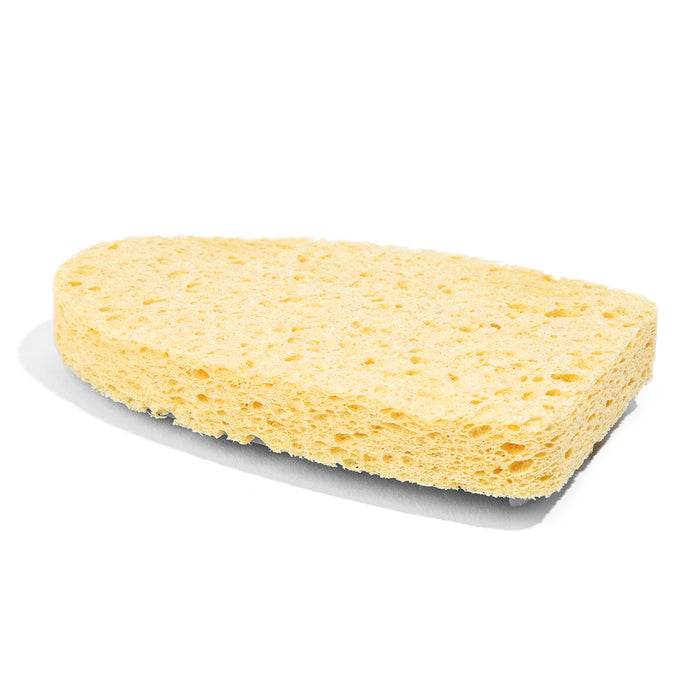A yellow, oval-shaped sponge with a porous texture is shown on a white background, casting a soft shadow below it.
