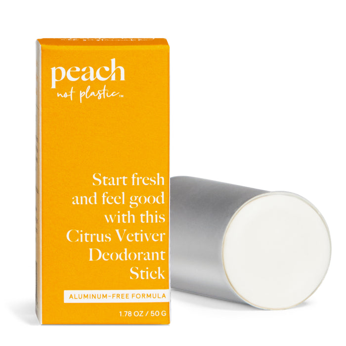 A yellow box labeled Peach not plastic and Citrus Vetiver Deodorant Stick stands next to a silver, cylindrical deodorant stick with a white top. The box highlights it is an aluminum-free formula.