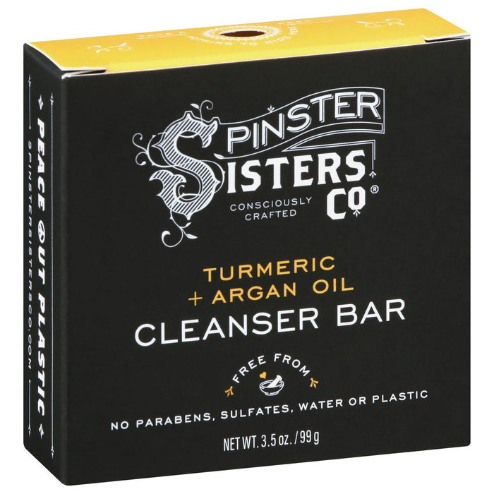 A black box of Spinster Sisters Co. Cleanser Bar with turmeric and argan oil, labeled “free from parabens, sulfates, water or plastic.” The packaging features white and yellow text and decorative accents.