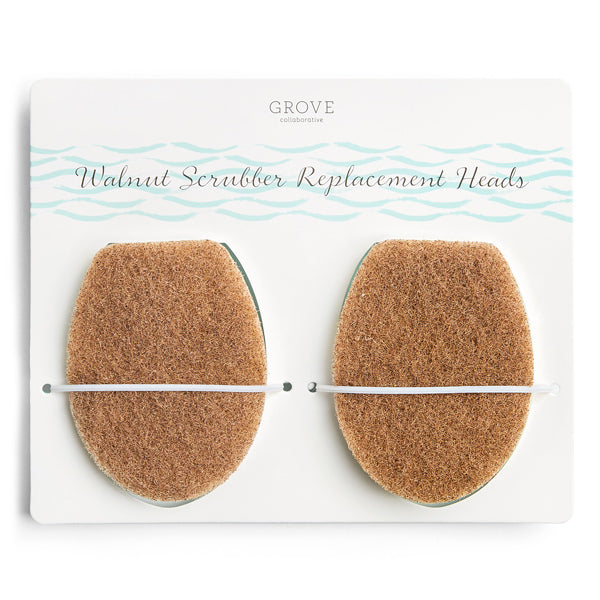 Two oval-shaped walnut scrubber replacement heads are attached to a white card labeled Walnut Scrubber Replacement Heads from Grove Collaborative, with light blue wave designs at the top.