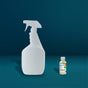 A large reusable Grove Collaborative glass spray bottle stands beside a small Tub & Tile Cleaner Starter Set bottle against a teal background, highlighting their size difference—ideal for storing your plant-based cleaner.