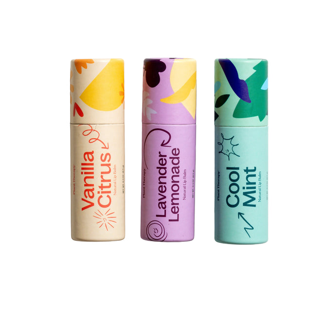 The Love Your Lips Trio Set by Plant Therapy features three vibrant lip balms in upright tubes with natural ingredients. Labels display Vanilla Citrus, Lavender Lemonade, and Cool Mint in orange, purple, and teal abstract patterns—ideal for naturally moisturizing your lips.