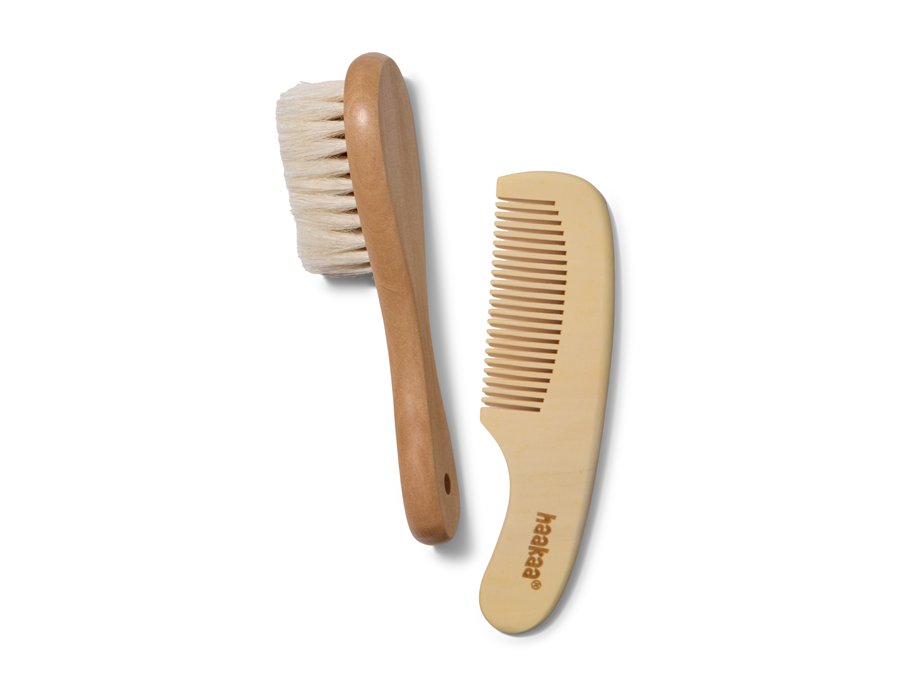 A wooden baby hairbrush with soft bristles and a matching wooden comb, both placed on a white background. The comb has haakaa printed on it.
