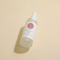 A frosted glass spray bottle of Wildcraft Balance Toner, a hydrating toner with neroli and aloe vera, rests on a light beige surface. The white label features a pink circular logo and black text, casting a soft shadow.