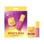The Burt’s Bees Lip Butter & Lip Oil Festive Treats Gift Set, featuring pomegranate lip butter and pink sky lip oil made with clean ingredients, is displayed in front of a purple and yellow gift box adorned with product images and the Burt’s Bees logo.
