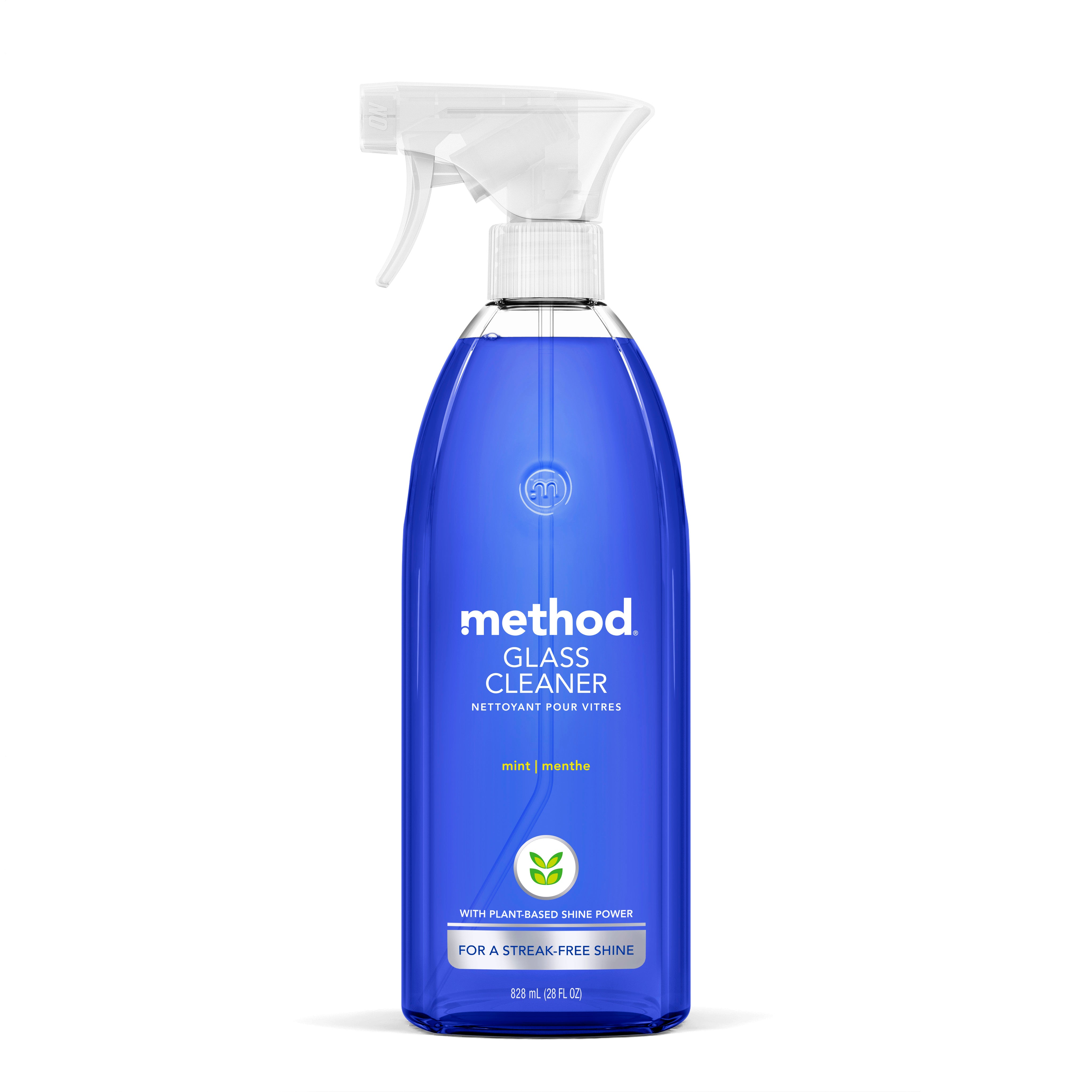 A blue spray bottle of method Glass Cleaner features a white nozzle and cap. The label, in English and French, highlights a mint scent and an ammonia-free, plant-based formula for streak-free shine. A green leaf icon adorns the label.