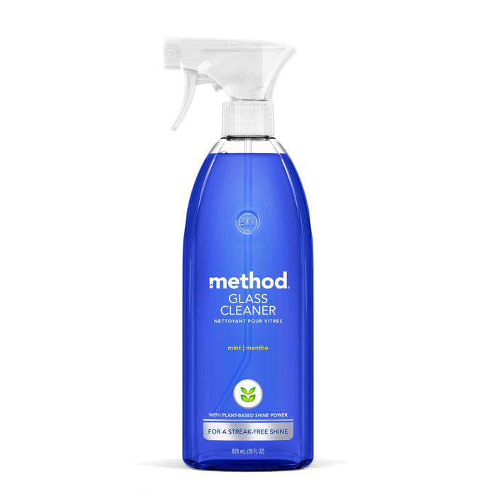 A clear spray bottle of Method Glass Cleaner with blue liquid, featuring a white spray nozzle and a front label with white and green text, highlighting mint scent and plant-based shine power.