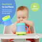 Baby in a high chair holding a blue silicone snack cup with a suction base by Morepeas. Text reads Suctions to surface – top lid reverses as suction base for less spills. 6+ months.