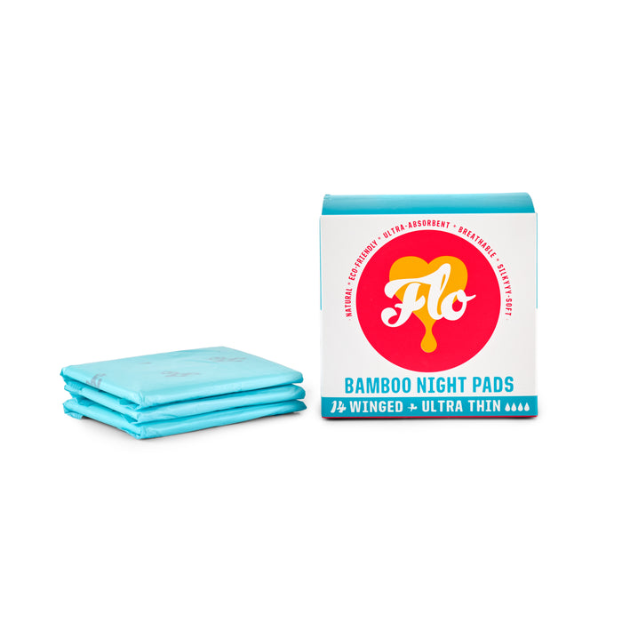 A package of FLO Bamboo Night Pads from Here We Flo is displayed, showcasing blue, ultra-thin pads with wings. The white box features red and yellow branding that highlights their ultra-absorbent protection and eco-friendly nature, made from organic bamboo.
