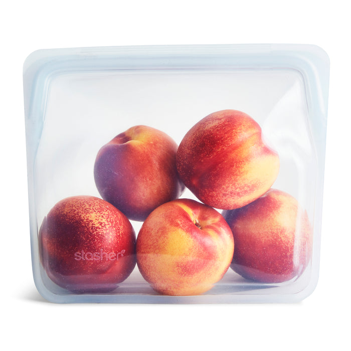 Five ripe nectarines inside a clear, reusable silicone storage bag with a light blue seal, set against a white background.