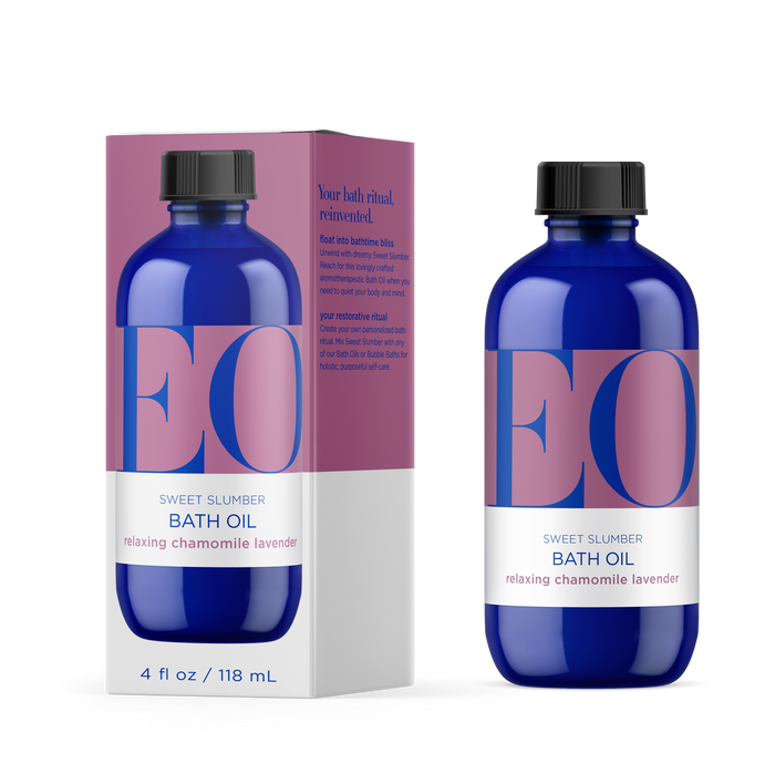 A blue bottle and matching box of EO Sweet Slumber Bath Oil with relaxing chamomile and lavender, featuring large pink and blue letters and a white label; the bottle contains 4 fl oz (118 mL).